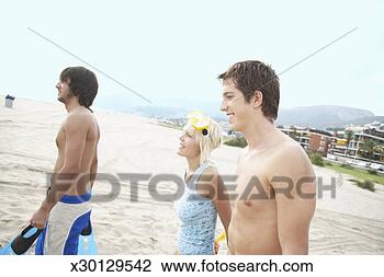Stock Photo - young woman and 
two young men 
walking on beach, 
man smiling. fotosearch 
- search stock 
photos, pictures, 
images, and photo 
clipart