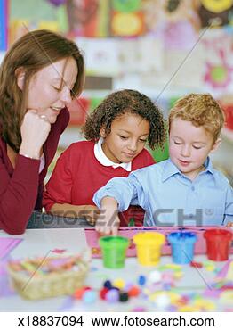 Stock Photo - schoolboy (4-6) 
painting, watched 
by teacher and 
schoolgirl (4-6). 
fotosearch - search 
stock photos, 
pictures, images, 
and photo clipart