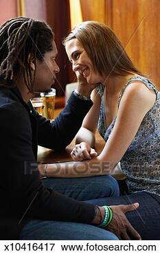 Picture - couple sitting 
face to face at 
table in bar, 
man touching woman's 
face. fotosearch 
- search stock 
photos, pictures, 
images, and photo 
clipart