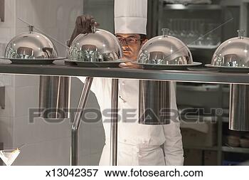 Picture - chef lifting lid 
from food on counter 
in hotel kitchen. 
fotosearch - search 
stock photos, 
pictures, images, 
and photo clipart