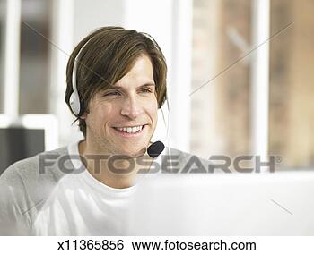 Stock Photo - man wearing headset 
at work, behind 
computer. fotosearch 
- search stock 
photos, pictures, 
images, and photo 
clipart