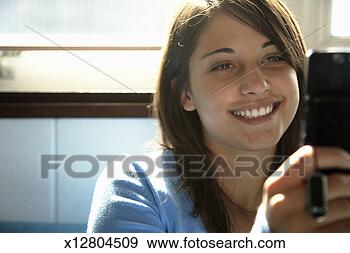 Stock Photograph - teenage girl (15-17) 
using mobile phone, 
smiling (focus 
on girl). fotosearch 
- search stock 
photos, pictures, 
images, and photo 
clipart