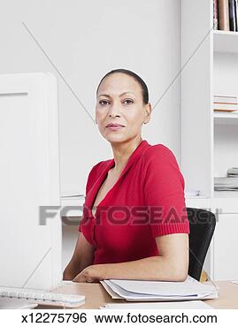 Stock Photo - business woman 
sitting behind 
desk, portrait. 
fotosearch - search 
stock photos, 
pictures, images, 
and photo clipart