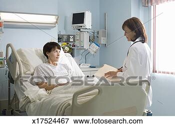 Picture - female doctor 
talking to female 
patient lying 
in hospital bed. 
fotosearch - search 
stock photos, 
pictures, images, 
and photo clipart