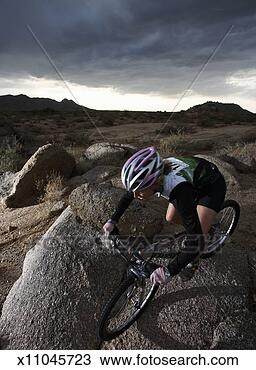 Stock Photo - female rider mountain 
biking between 
rocks, elevated 
view. fotosearch 
- search stock 
photos, pictures, 
images, and photo 
clipart