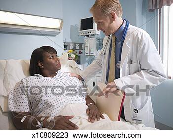 Stock Photo - male doctor talking 
to female patient 
lying in hospital 
bed. fotosearch 
- search stock 
photos, pictures, 
images, and photo 
clipart