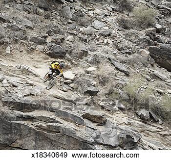 Stock Photograph - man mountain biking 
down rocky mountain 
slope, elevated 
view. fotosearch 
- search stock 
photos, pictures, 
images, and photo 
clipart