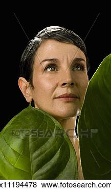 Stock Photo - mature woman behind 
two large leaves 
on black background. 
fotosearch - search 
stock photos, 
pictures, images, 
and photo clipart