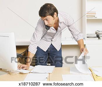 Picture - office worker 
using phone and 
computer in office. 
fotosearch - search 
stock photos, 
pictures, images, 
and photo clipart