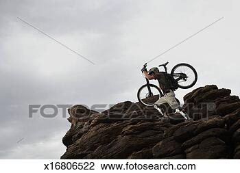 Stock Photo - rider carrying 
mountain bike 
to mountain peak, 
low angle view. 
fotosearch - search 
stock photos, 
pictures, images, 
and photo clipart