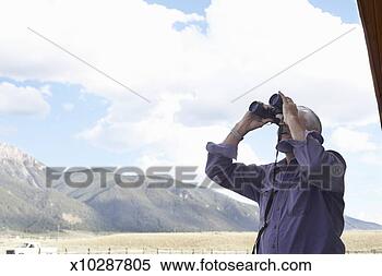Stock Image - senior man looking 
through binoculars 
outdoors. fotosearch 
- search stock 
photos, pictures, 
images, and photo 
clipart