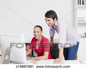 Stock Photography - two office workers 
using computer 
in office, elevated 
view. fotosearch 
- search stock 
photos, pictures, 
images, and photo 
clipart