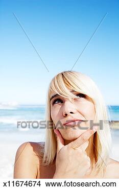 Stock Photo - young woman on 
beach, looking 
up with hand on 
chin, close-up. 
fotosearch - search 
stock photos, 
pictures, images, 
and photo clipart