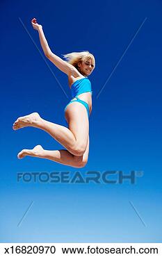 Stock Photography - young woman in 
bikini leaping 
against blue sky, 
low angle view. 
fotosearch - search 
stock photos, 
pictures, images, 
and photo clipart