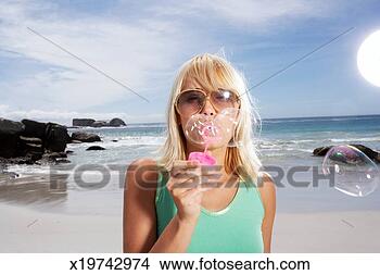 Stock Photo - young woman blowing 
soap bubbles on 
beach, portrait. 
fotosearch - search 
stock photos, 
pictures, images, 
and photo clipart