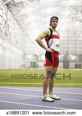 Stock Photography - male track athlete 
standing on indoor 
track, hands on 
hips, portrait. 
fotosearch - search 
stock photos, 
pictures, images, 
and photo clipart