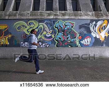 Stock Photo - young man jogging 
past graffiti 
wall. fotosearch 
- search stock 
photos, pictures, 
images, and photo 
clipart