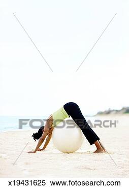 Stock Image - woman on beach 
practicing yoga 
with fitness ball. 
fotosearch - search 
stock photos, 
pictures, images, 
and photo clipart