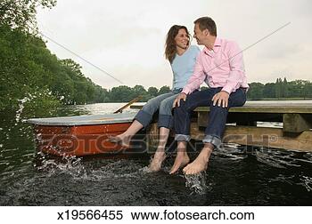 Stock Image - germany, potsdam, 
couple sitting 
on jetty, dangling 
feet in water. 
fotosearch - search 
stock photos, 
pictures, images, 
and photo clipart