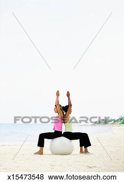 Stock Photo - two women on beach 
using fitness 
ball to practice 
yoga, profile. 
fotosearch - search 
stock photos, 
pictures, images, 
and photo clipart