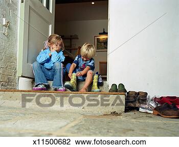 Stock Photo - boy and girl (3-5) 
on doorstep, boy 
putting on rubber 
boot. fotosearch 
- search stock 
photos, pictures, 
images, and photo 
clipart