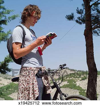 Stock Photo - young man on mountain 
bike looking at 
guide book, close-up. 
fotosearch - search 
stock photos, 
pictures, images, 
and photo clipart