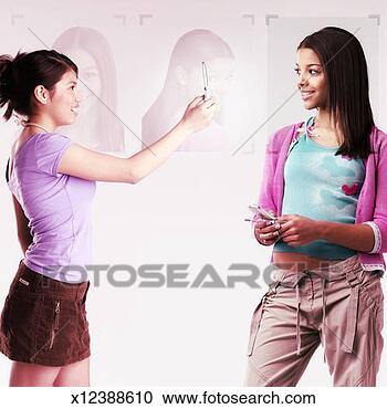 Stock Photography - two teenage girls 
(13-15) with cell 
phones, one girl 
taking photograph. 
fotosearch - search 
stock photos, 
pictures, images, 
and photo clipart