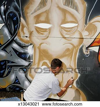 Stock Photography - young man spray 
painting graffiti 
piece, rear view. 
fotosearch - search 
stock photos, 
pictures, images, 
and photo clipart