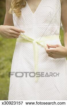Picture - young woman in 
dress tying bow 
around waist, 
mid section. fotosearch 
- search stock 
photos, pictures, 
images, and photo 
clipart