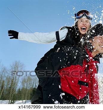 Stock Photograph - young man giving 
young woman piggyback 
ride, snowball 
hitting woman. 
fotosearch - search 
stock photos, 
pictures, images, 
and photo clipart