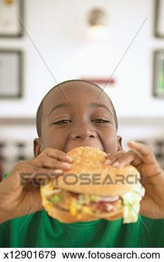 Stock Photograph - boy (5-7) biting 
into hamburger, 
portrait (focus 
on boy's face). 
fotosearch - search 
stock photos, 
pictures, images, 
and photo clipart