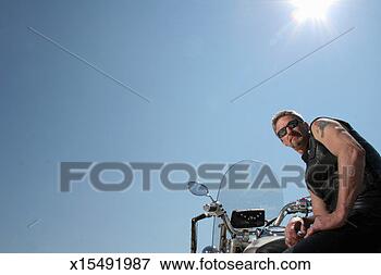 Picture - mature man sitting 
on stationary 
motorbike, low 
angle view. fotosearch 
- search stock 
photos, pictures, 
images, and photo 
clipart