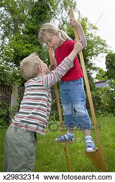 Stock Photo - boy (4-6) holding 
up girl (4-6) 
on stilts outdoors. 
fotosearch - search 
stock photos, 
pictures, images, 
and photo clipart