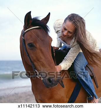Stock Photo - young woman sitting 
on horse by ocean, 
patting horse's 
head. fotosearch 
- search stock 
photos, pictures, 
images, and photo 
clipart