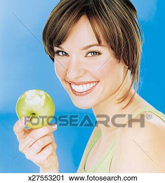 Stock Photography - young woman holding 
half eaten apple, 
smiling, portrait, 
close-up. fotosearch 
- search stock 
photos, pictures, 
images, and photo 
clipart