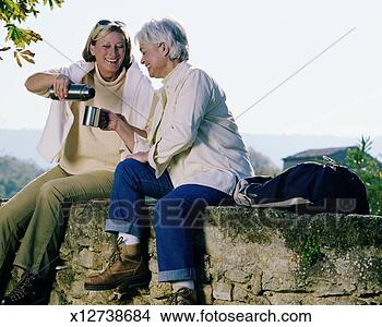 Stock Photo - two mature women 
sitting on stone 
wall sharing beverage. 
fotosearch - search 
stock photos, 
pictures, images, 
and photo clipart
