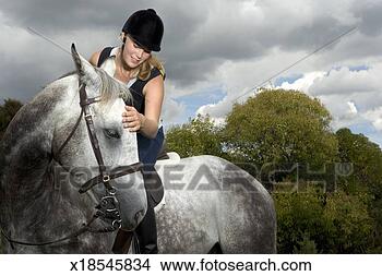 Stock Photo - teenage girl (17-19) 
sitting on horse, 
stroking horse's 
forehead. fotosearch 
- search stock 
photos, pictures, 
images, and photo 
clipart