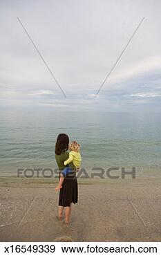 Stock Photograph - mexico, baja, 
mother holding 
daughter (2-4) 
on beach, rear 
view. fotosearch 
- search stock 
photos, pictures, 
images, and photo 
clipart