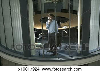 Stock Photo - businessman using 
telephone facing 
window of conference 
room. fotosearch 
- search stock 
photos, pictures, 
images, and photo 
clipart