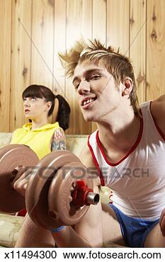 Stock Photography - young man and 
woman on sofa, 
man lifting barbell 
(focus on man). 
fotosearch - search 
stock photos, 
pictures, images, 
and photo clipart