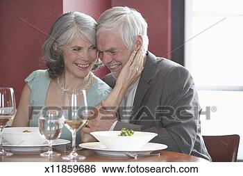 Stock Photo - mature man and 
woman laughing 
in restaurant, 
woman touching 
man's face. fotosearch 
- search stock 
photos, pictures, 
images, and photo 
clipart