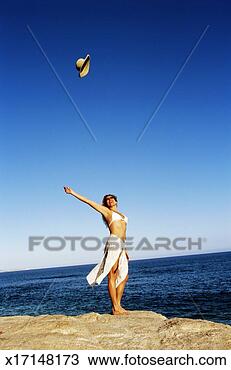 Stock Photo - woman by sea tossing 
hat into air. 
fotosearch - search 
stock photos, 
pictures, images, 
and photo clipart
