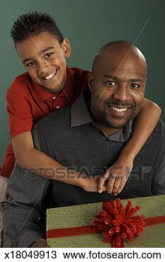 Stock Photo - father and son 
(10-12) smiling, 
father holding 
gift, portrait. 
fotosearch - search 
stock photos, 
pictures, images, 
and photo clipart