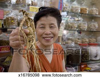 Stock Photo - senior woman holding 
ginseng root in 
herbal medicine 
store, portrait. 
fotosearch - search 
stock photos, 
pictures, images, 
and photo clipart