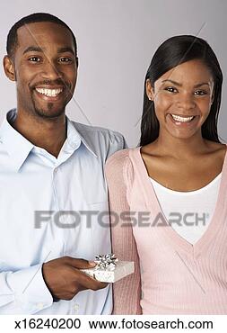 Stock Photography - young man and 
woman smiling, 
man holding gift, 
portrait. fotosearch 
- search stock 
photos, pictures, 
images, and photo 
clipart