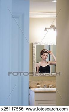 Stock Photo - young woman styling 
hair in bathroom 
mirror, view through 
doorway. fotosearch 
- search stock 
photos, pictures, 
images, and photo 
clipart