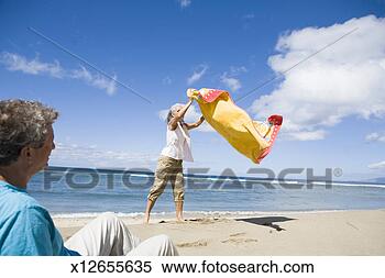 Stock Image - mature man watching 
mature woman place 
blanket on sandy 
beach. fotosearch 
- search stock 
photos, pictures, 
images, and photo 
clipart