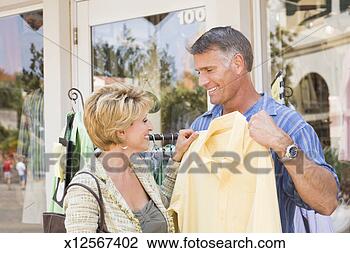 Stock Photo - mature woman holding 
shirt up to mature 
man in front of 
retail store. 
fotosearch - search 
stock photos, 
pictures, images, 
and photo clipart