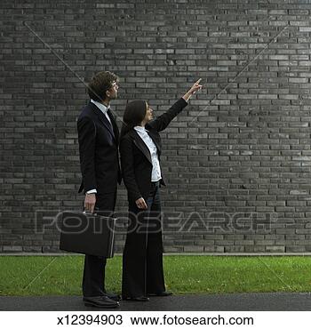 Stock Photo - business woman 
pointing to sky, 
business man watching, 
side view. fotosearch 
- search stock 
photos, pictures, 
images, and photo 
clipart