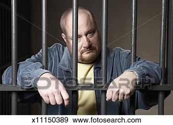 Stock Photograph - bald mid-adult 
man standing behind 
prison bars. fotosearch 
- search stock 
photos, pictures, 
images, and photo 
clipart